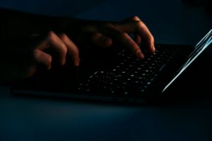 Person examining a suspicious email on a laptop beside a smartphone and handwritten notes.