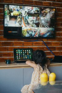 Family watches a television while a router and streaming device sit on a nearby shelf.